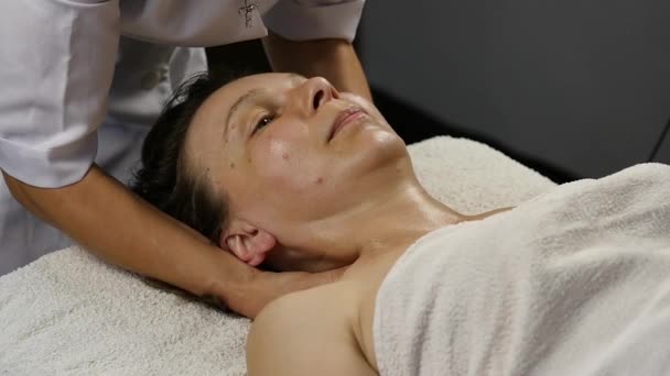 Женщина-врач делает антивозрастной массаж клиенту. женщине нравится пластический массаж лица в спа-сатоне. замедленное движение — стоковое видео