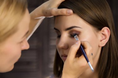 Göz makyaj kadın göz farı toz uygulamak. Stilist yapmak için erkek eyeliner tarafından yapıyor
