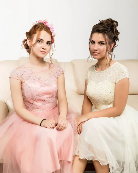 두 매력적인 젊은 여자는 소파에 앉아 우아한 드레스에 부드러운 역사 — 스톡 사진