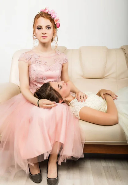 두 매력적인 젊은 여자는 소파에 앉아 우아한 드레스에 부드러운 역사 — 스톡 사진