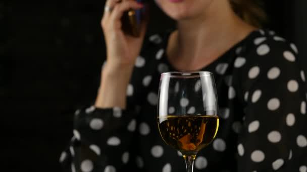 Encantadora mujer hablando por teléfono celular y bebiendo vino en una oscuridad. ambiente festivo y concepto de celebración. 4K — Vídeo de stock