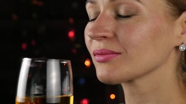 魅力的な若い女性が、暗闇の中で白ワインを飲みます。お祭りの雰囲気とお祝いのコンセプトです。スローモーション — ストック動画