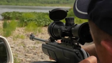 Bir vahşi doğa tatil sırasında optik görüş bir havalı tüfek silahla ateş adam. ağır çekim