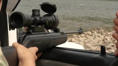 Bir vahşi doğa tatil sırasında optik görüş bir havalı tüfek silahla ateş adam. ağır çekim