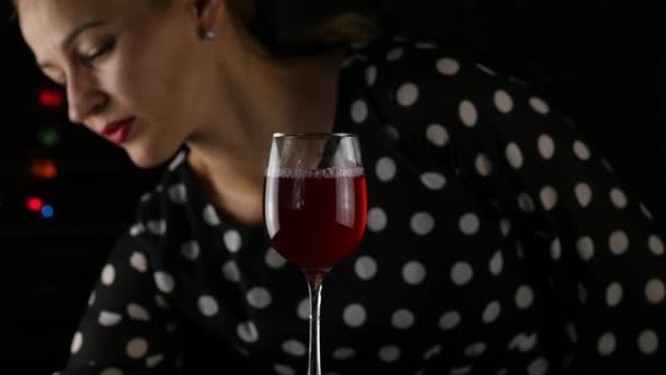 Mooie jonge vrouw drinken van rode wijn in een donker. schoonheid dame met glas wijn. Slow motion — Stockvideo