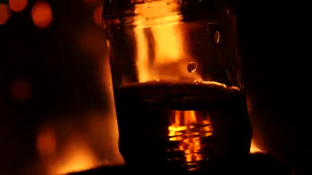 Bouteille de bière sur fond de feu dans un noir. jeu de flamme sur verre brun. 4K — Video