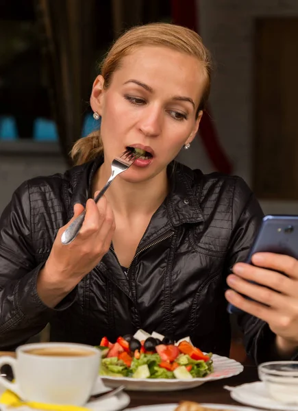 Üzletasszony, salátát eszik egy szabadtéri kávézó. Egészséges életmód: lány eszik zöld ízletes ételek és ellenőrzések e-mailt a telefon — Stock Fotó