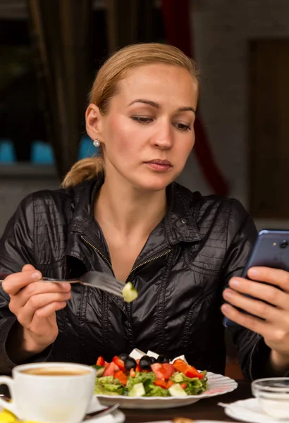 Обед в кафе на открытом воздухе. деловая женщина ест салат и проверяет почту на вашем телефоне — стоковое фото