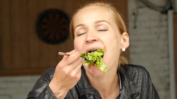 Kobieta interesu jedzeniu sałatkę w kawiarnię na świeżym powietrzu. Dziewczyna, jeść zielone smaczne jedzenie i kontroli e-mail w telefonie. zwolnionym tempie — Wideo stockowe