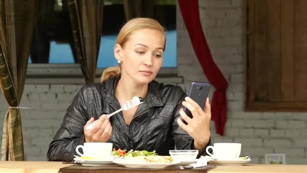 在户外咖啡馆吃午饭。女商人在你的手机上吃沙拉和检查电子邮件。慢动作 — 图库视频影像