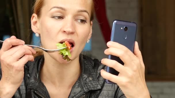 Lunch in een buitencafé. zakenvrouw eten salade en controles e-mail op uw telefoon. Slow motion — Stockvideo