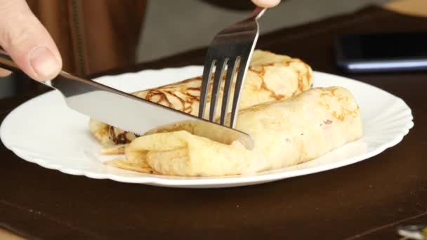 Lunch op het zomerterras. iemand eet pannenkoeken met een mes en vork. 4k — Stockvideo