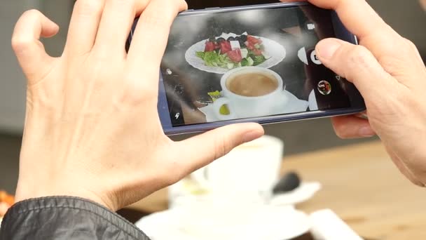 Kvinne på utendørs kafe tar et bilde av salat og kopp kaffe. langsom bevegelse – stockvideo