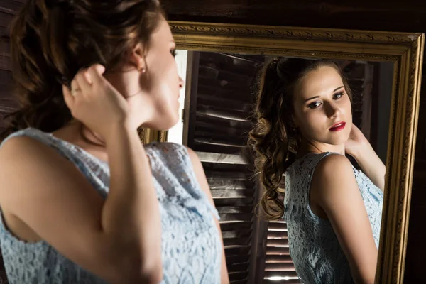 Jeune femme élégante devant miroir, or et bois — Photo