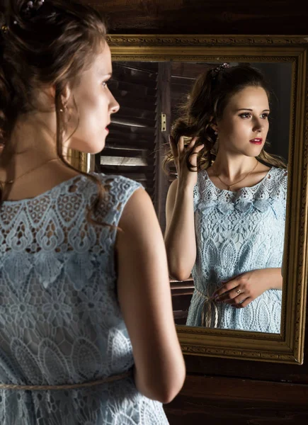 Młoda kobieta elegancka przed lustrem, złota i drewna — Zdjęcie stockowe