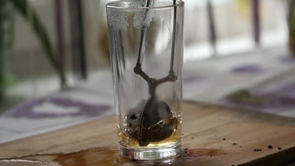 Glas mit heißem Wasser mit einem Tee-Ei. Tee zubereiten. Zeitlupe — Stockvideo