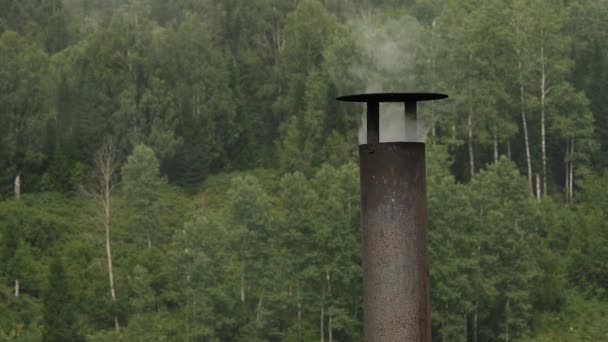 Dym pochodzi z żelaza komina domu. Kominy na tle drzew. zwolnionym tempie — Wideo stockowe