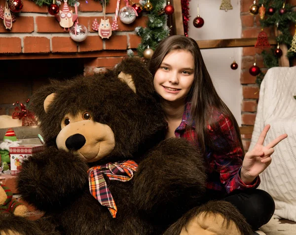 Teenagermädchen umarmt großen Teddybär an Weihnachten in der Nähe von Kamin — Stockfoto