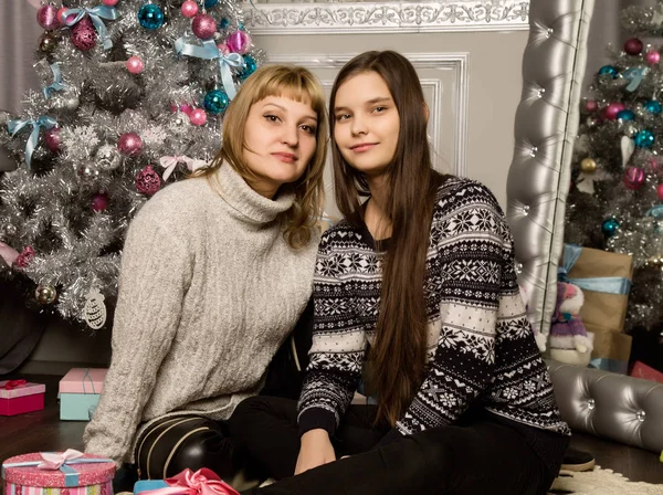 Šťastný matka a dcera teenag poblíž vánoční stromeček doma smát a obejmout — Stock fotografie