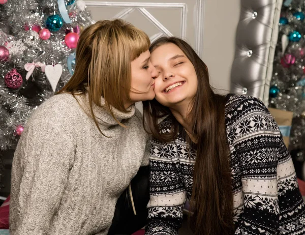 Щаслива мати і дочка-підліток біля ялинки вдома сміються і обіймаються — стокове фото