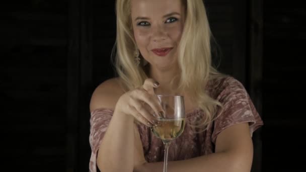 Самотня розкішна блондинка п'є шампанське в темряві на вечірці. повільний рух — стокове відео