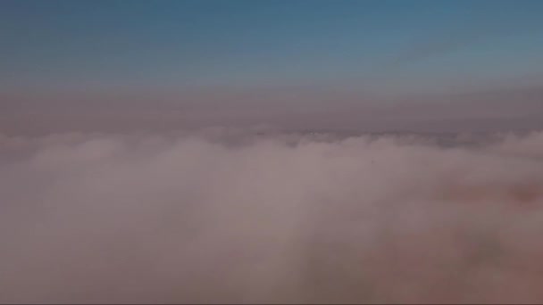 Luchtfoto, vliegen door en over de mist bij zonsondergang, landschap met een weg — Stockvideo