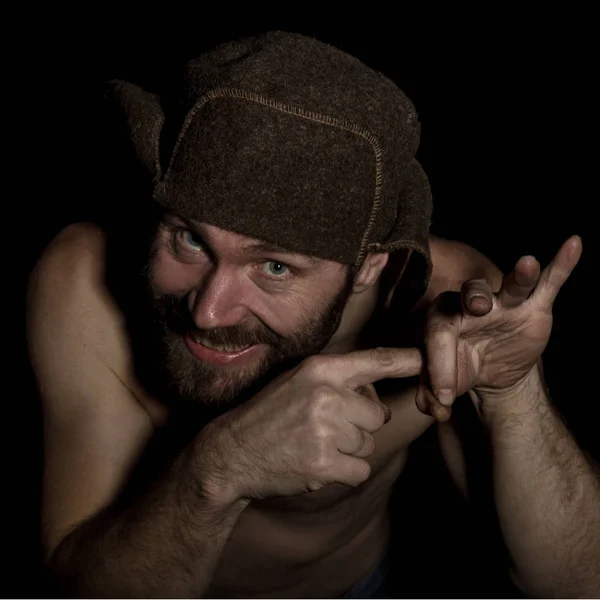 Странный русский мужчина с обнаженным туловищем и шерстяной шляпой, делающий разные знаки руками . — стоковое фото
