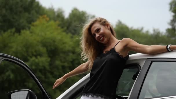 Jolie femme blonde près d'une porte de voiture ouverte. La conductrice pose. au ralenti — Video