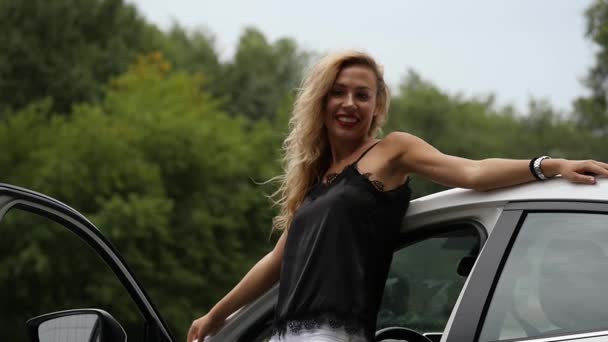 Attractive blonde woman near an open car door. female driver is posing. slow motion — Stock Video