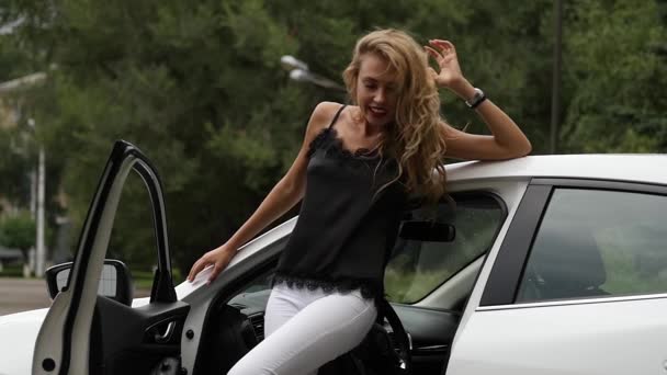 Привлекательная блондинка рядом с открытой дверью машины. Женщина-водитель позирует. замедленное движение — стоковое видео