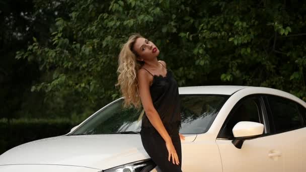 Schöne junge blonde Frau mit langen Haaren, die neben weißem Auto steht. — Stockvideo