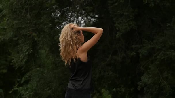 Vue arrière de la femme blonde sur fond de nature. Belle fille pose avec des cheveux volants. au ralenti — Video