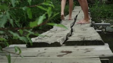 Gençler bacaklar bir dağ nehir üzerinde dar bir ahşap köprü yürüyüş. kamp ve macera kavramı