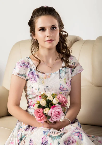 Wanita muda lucu dengan bunga duduk di sofa, gaya rambut profesional dengan karangan bunga . — Stok Foto