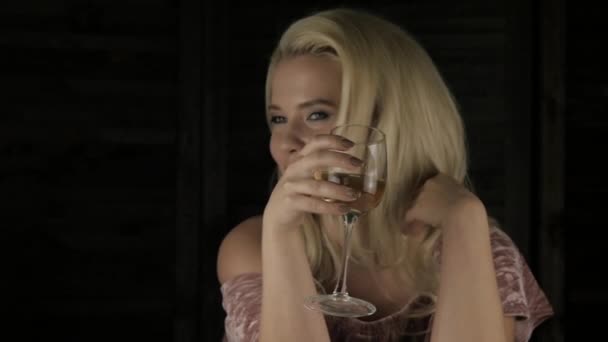 Close-up blonde vrouw drinkt champagne alleen in het donker. eenzame luxe meisje in restauran. Slow motion — Stockvideo