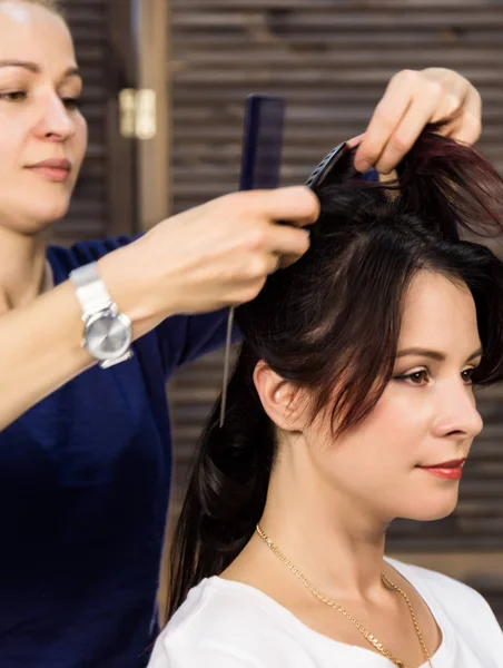 Парикмахер делает прическу для роскошной женщины. coiffure in the form of big curl. Концепция свадебной прически — стоковое фото