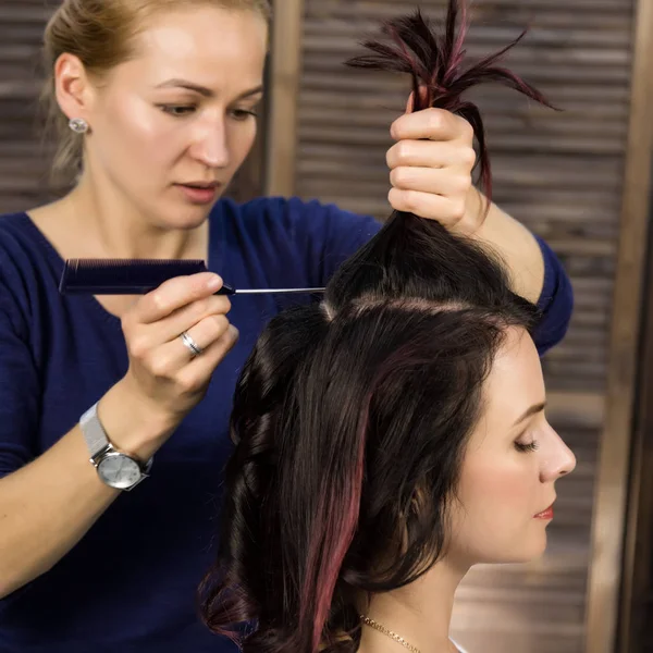 Парикмахер делает прическу для роскошной женщины. coiffure in the form of big curl. Концепция свадебной прически — стоковое фото