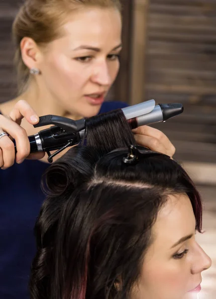 Парикмахер делает прическу для роскошной женщины. coiffure in the form of big curl. Концепция свадебной прически — стоковое фото