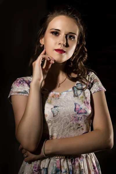 Jovem mulher elegante com profissional penteado poses em um fundo escuro . — Fotografia de Stock