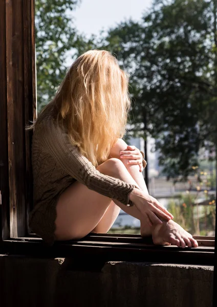 Mujer joven en una blusa corta cerca de una ventana rota en un edificio abandonado —  Fotos de Stock
