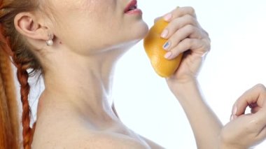 Genç kadının ağzına ve beyaz bir arka planda yavaş boynundaki portakal sıkma