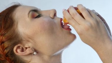 Genç kadının ağzına ve beyaz bir arka planda yavaş boynundaki portakal sıkma