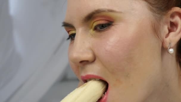 Młoda kobieta, ciesząc się na łóżku, za pomocą laptopa i jedzeniu bananów w domu w godzinach porannych. zwolnionym tempie — Wideo stockowe