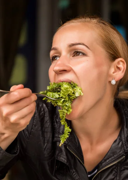 Деловая женщина ест салат в кафе на открытом воздухе. Здоровый образ жизни: девушка ест зеленую вкусную еду — стоковое фото