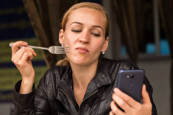 Empresária comendo salada em um café ao ar livre. Estilo de vida saudável: menina comendo comida verde saborosa e verifica e-mail em seu telefone — Fotografia de Stock