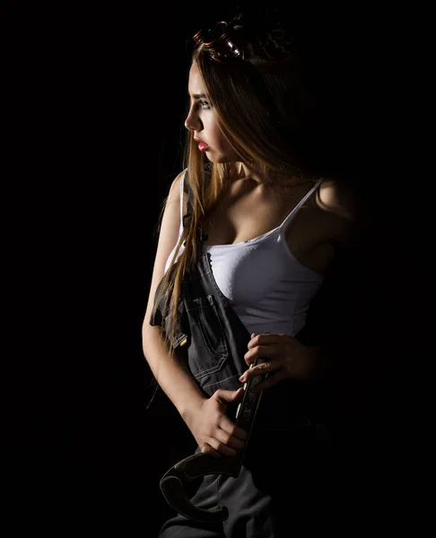 Молодая импульсивная сексуальная женщина, одетая как автомеханик и в сварных очках с большим гаечным ключом — стоковое фото