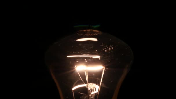 Light bulb turning on and off on black background, slow motion — Stock Video