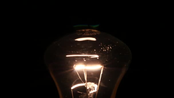 Light bulb draaien aan en uit op zwarte achtergrond, slow-motion — Stockvideo