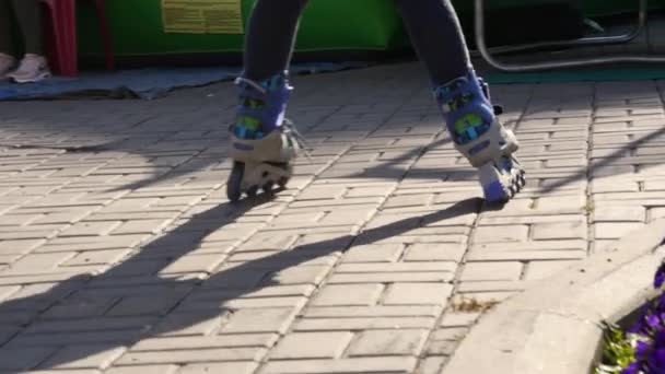 Legs of a child in roller skates. Child rolls in pablic park. Slow motion — Stock Video