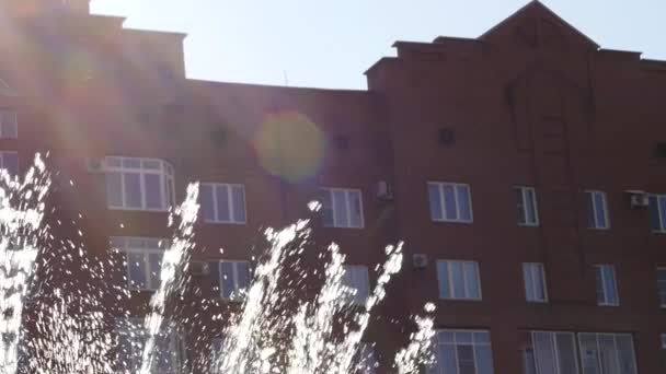 Streams of water of fountain on a city building background in sunny day. slow motion — Stock Video